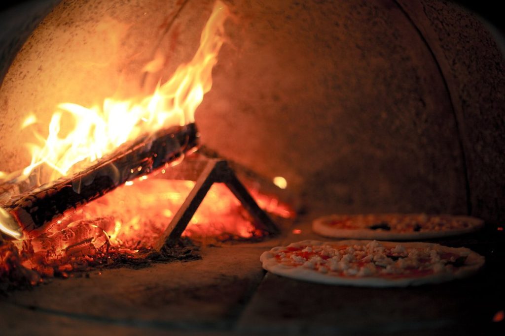 Fatüzelésű téglakemence lángokkal és pizzákkal – illusztráció