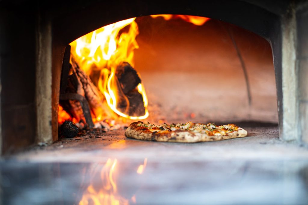 Pizza sül a fatüzelésű kemencében – illusztráció