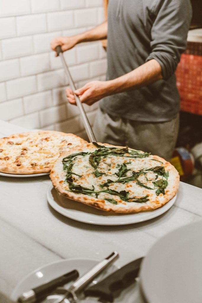 Pizzaiolo pizzát tesz a kemencébe – illusztráció