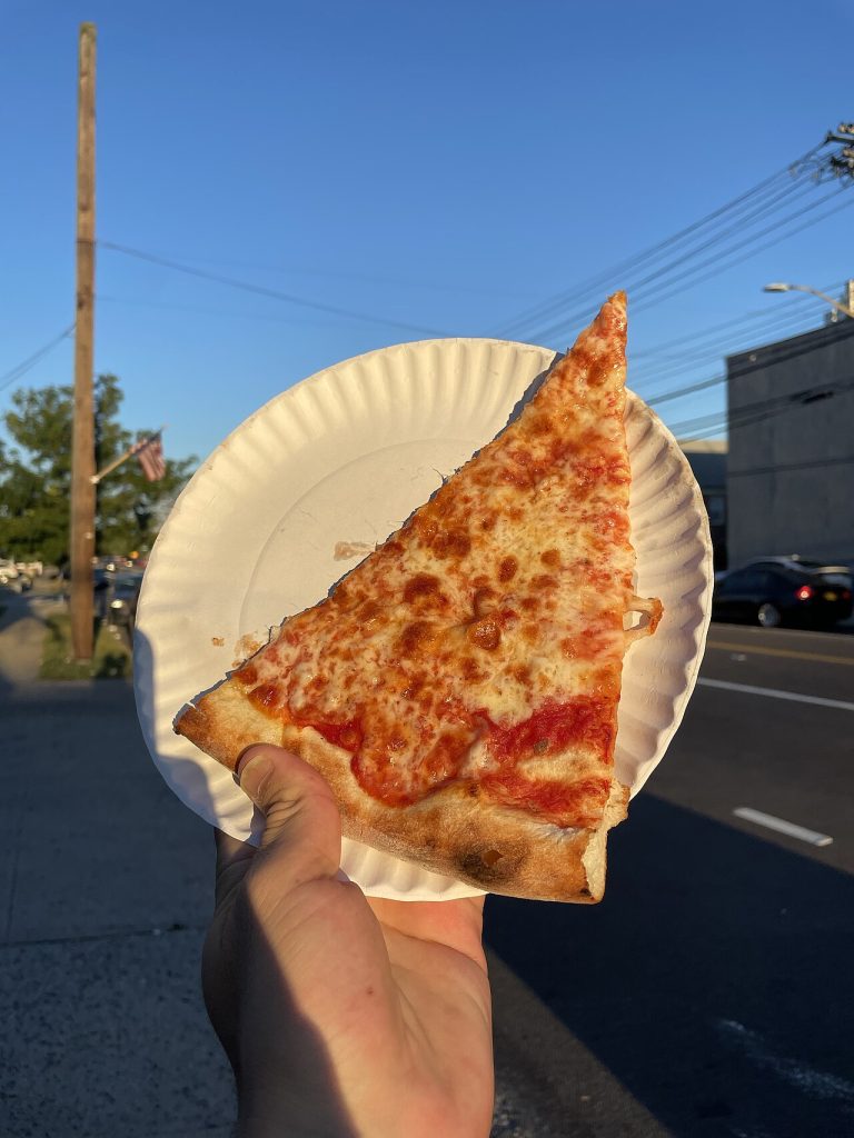 New York-i sajtos pizzaszelet papírtányéron