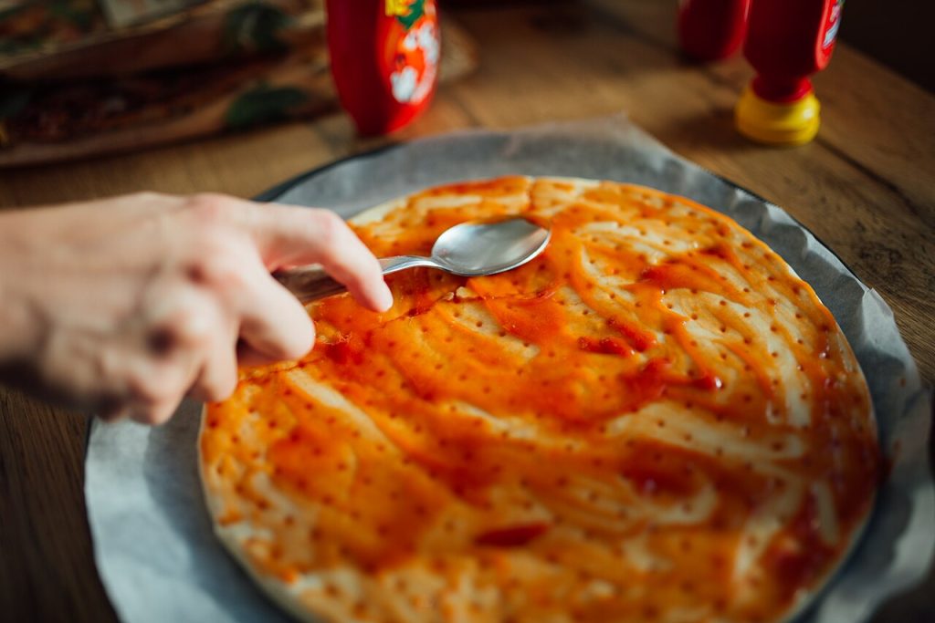 Paradicsomszósz kenése házi pizzatésztára